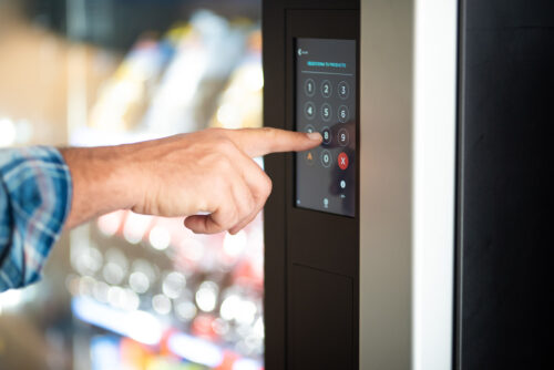 Close up of a man hand-typing a number onto a vending machine