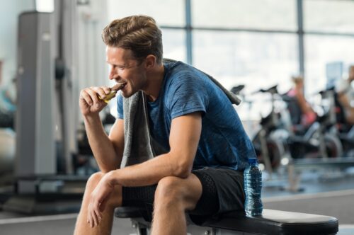 man eating snack from gym vending machine